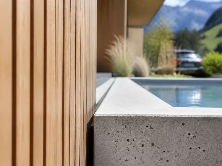 Präzise Holzfassade neben einer scharfkantigen Beckenkante aus Sichtbeton