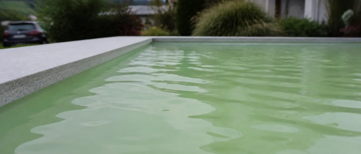 Trübes, milchig-grünes Poolwasser, in dem der Beckenboden nicht zu erkennen ist