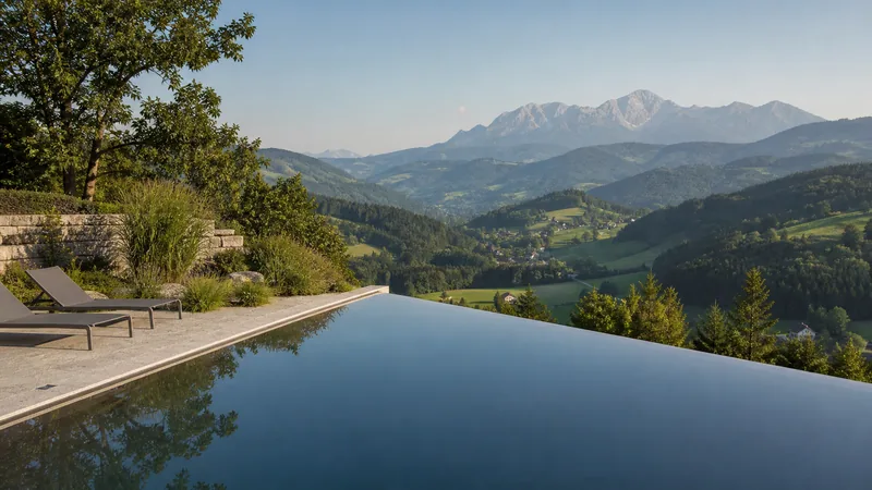 Infinity-Pool mit Überlaufkante vor weitem Talblick auf die Berge